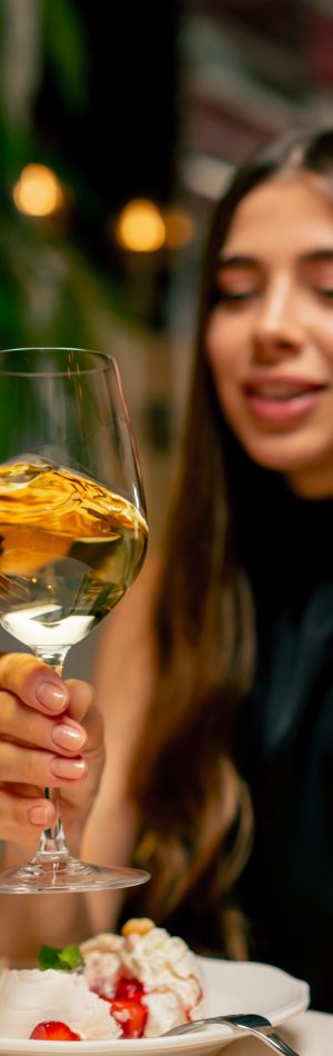 Close-up of a cute young girl drinking expensive delicious wine during a date in Italian restaurant